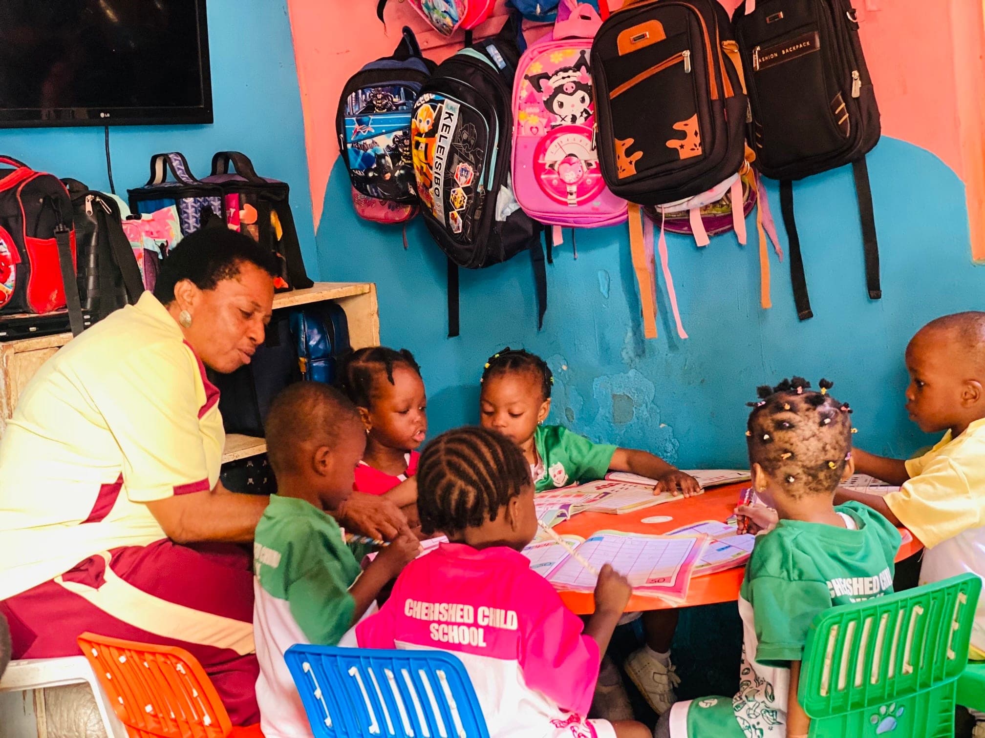 Nursery pupils working in their exercise books while their teacher supervises