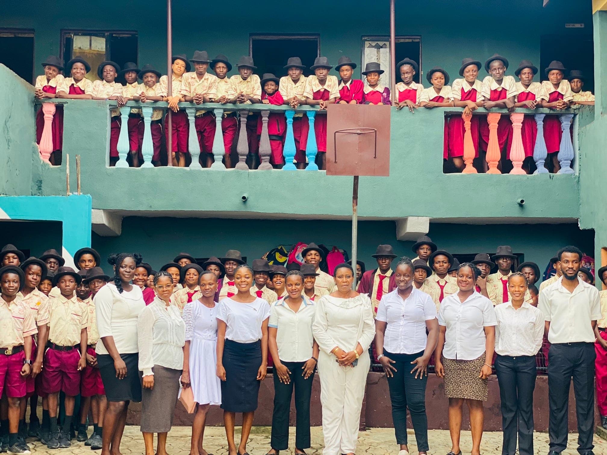Students of Nike-Cherished School lining the first-floor balcony above staff standing in the courtyard
