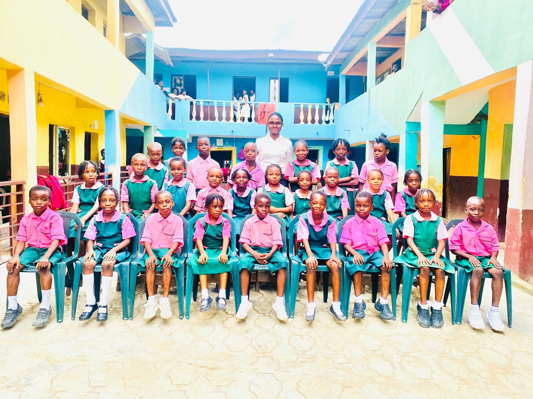 Primary pupils seated for a class photograph with their teacher standing behind