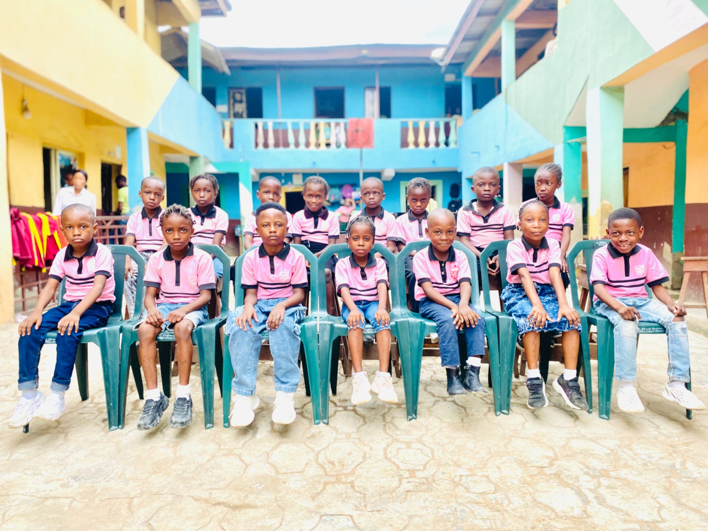 Primary pupils in pink polo shirts seated in the courtyard on a casual dress day