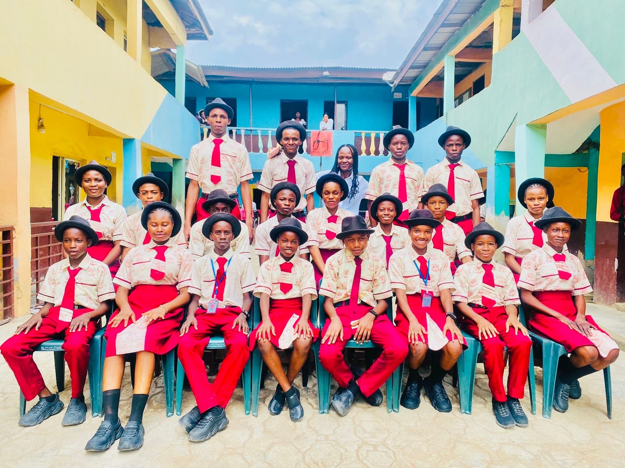 Secondary students in cream and wine uniform seated with their teacher